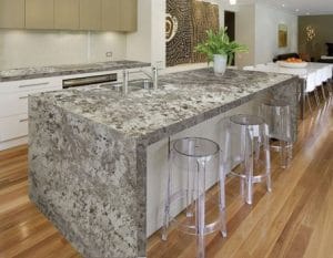 Gray granite-topped kitchen island with three transparent stools