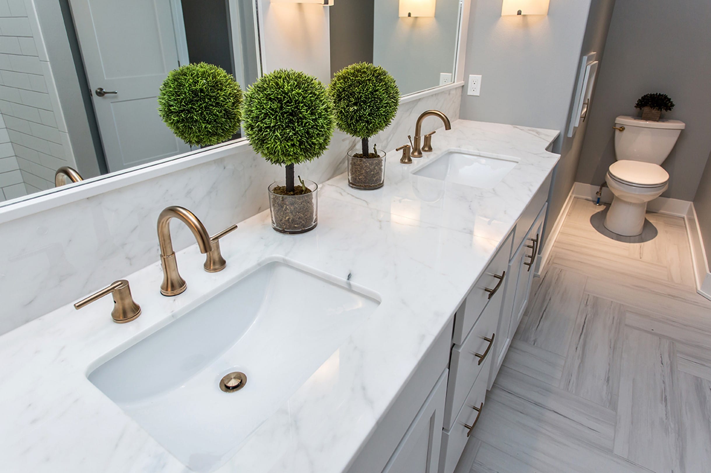 Marble vanity with metallic sinks and mirror on the wall